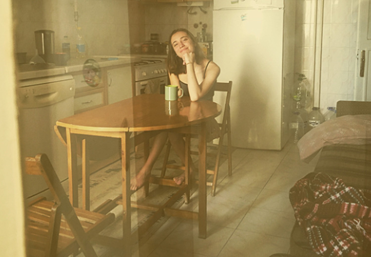 Doksanlarda bir evin sepya mutfağındaki katlanır masada oturan kız